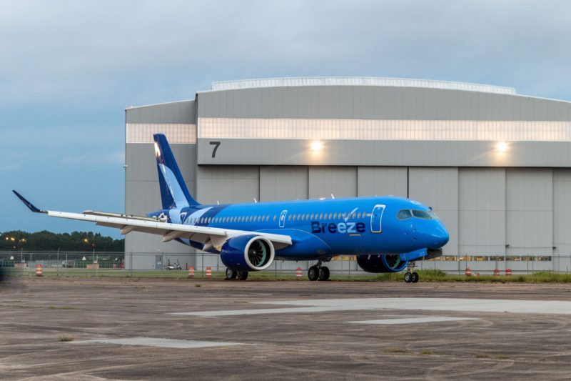 a blue airplane parked in front of a building