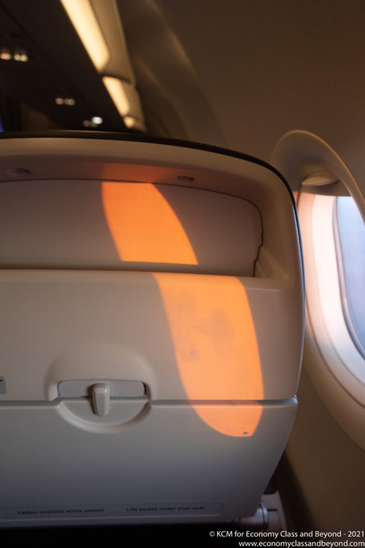 an airplane seat with a light reflecting off the window