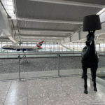 a black horse lamp in a room with a plane in the background