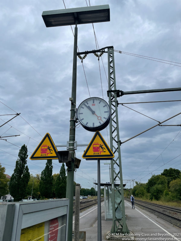 a clock on a pole next to a train track