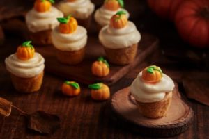 a group of cupcakes with frosting and pumpkins