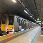 a woman sitting on a platform next to a train