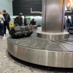 a group of people standing around a luggage carousel