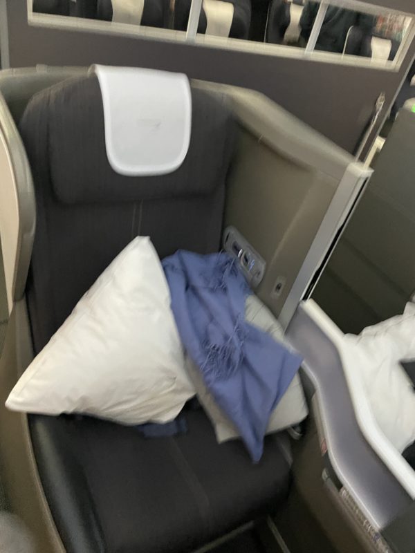a seat with pillows and a blue blanket