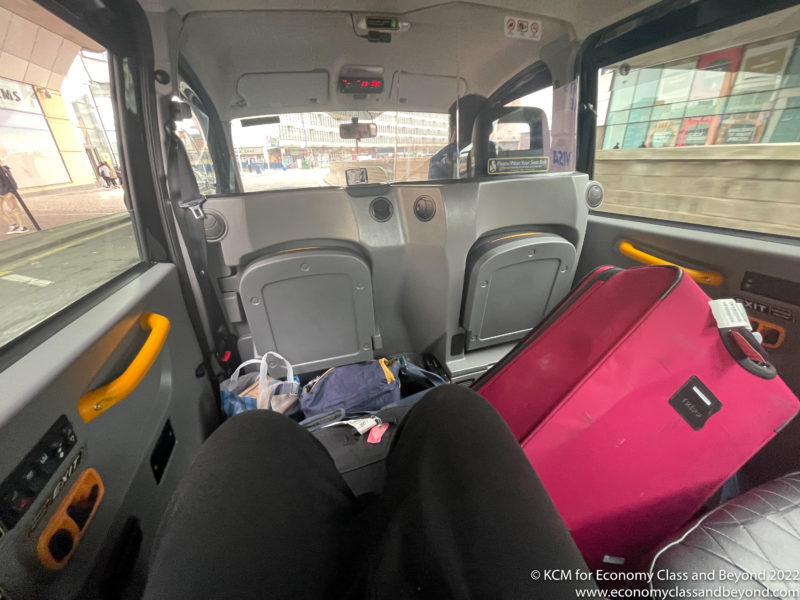 a person's legs in the back seat of a vehicle with luggage