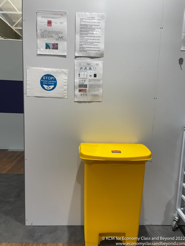 a yellow trash can next to a wall with papers on it