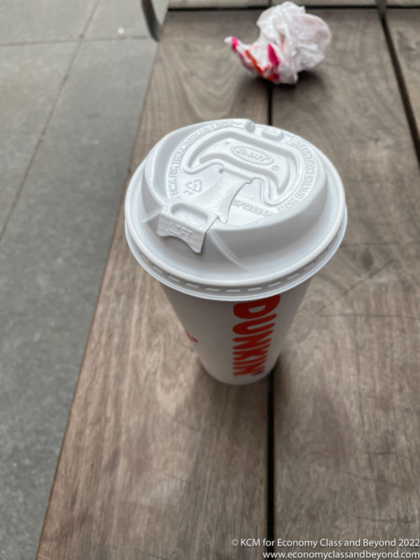 a white cup with a lid on a wooden surface