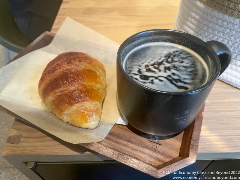 a croissant and a cup of coffee on a tray