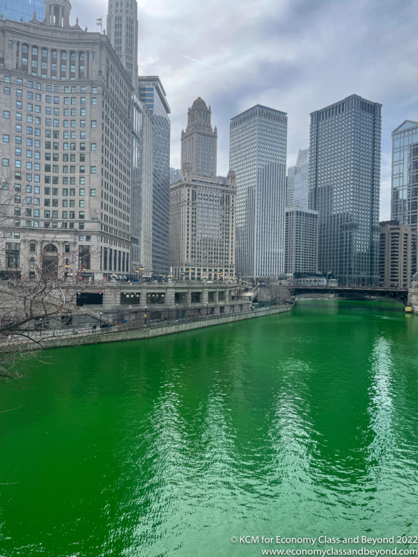 a green river with buildings in the background with Chicago River in the background