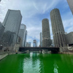 a green river with tall buildings in the background with Chicago River in the background