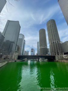 a green river with tall buildings in the background with Chicago River in the background