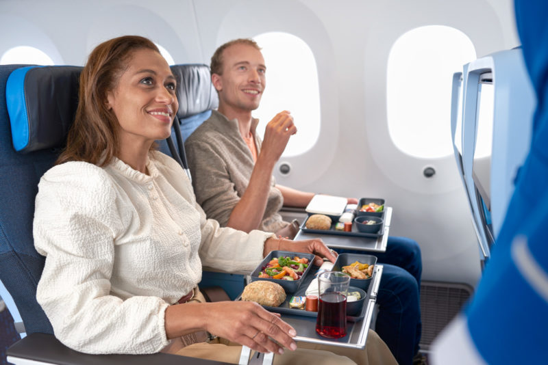 a man and woman sitting in an airplane eating food