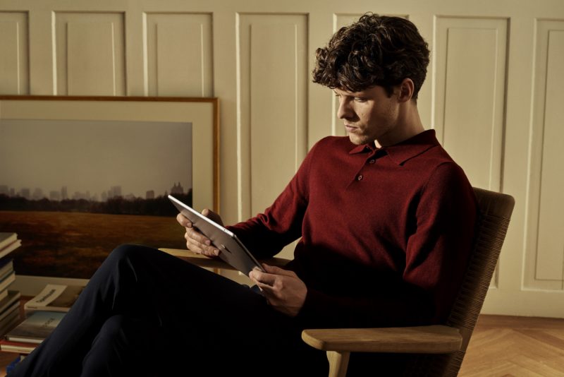 a man sitting in a chair looking at a tablet