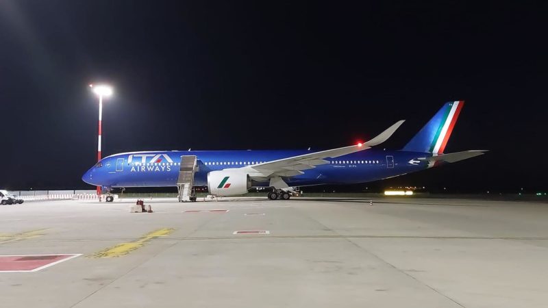 a blue airplane on a runway at night