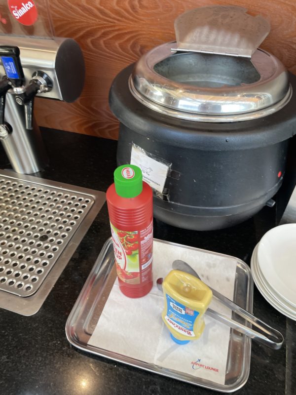 a container with sauce and a container with a lid on a tray