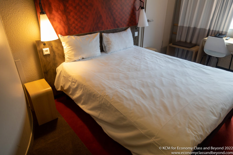 a bed with white sheets and two lamps