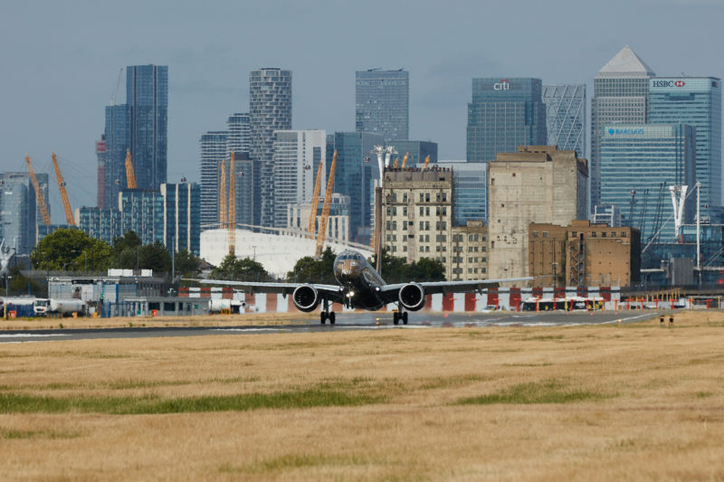 a plane taking off from a runway with a city in the background