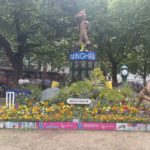 a flower garden with a statue of a man and a sign