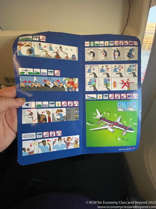 a hand holding a blue and white paper with a cartoon of flight instructions