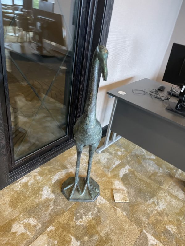 a statue of a bird in front of a glass door