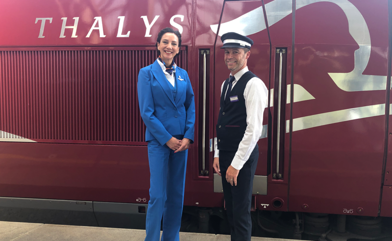 a man and woman in uniform standing in front of a train