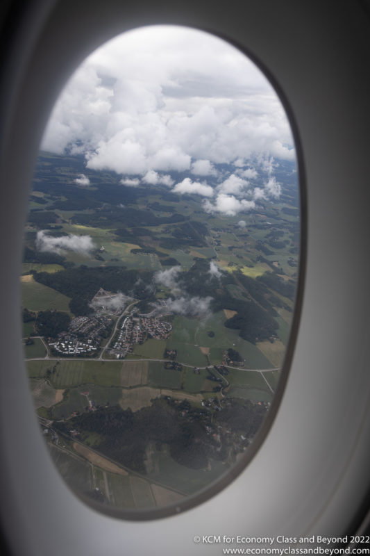 an airplane window with clouds and a landscape