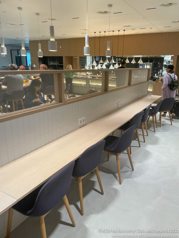 a long table with chairs in a room with people sitting in the background