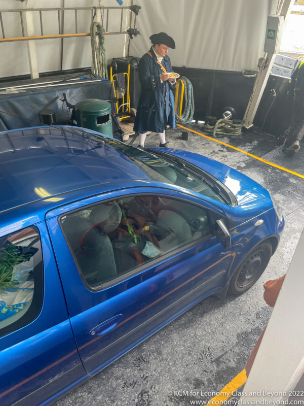 a woman standing in a garage with a blue car