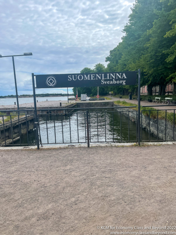 a sign with a gate and a body of water