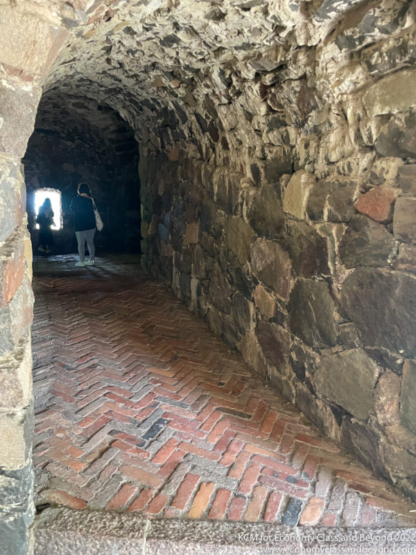 a stone tunnel with a brick walkway and a person standing in it