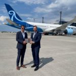 two men in suits standing in front of an airplane