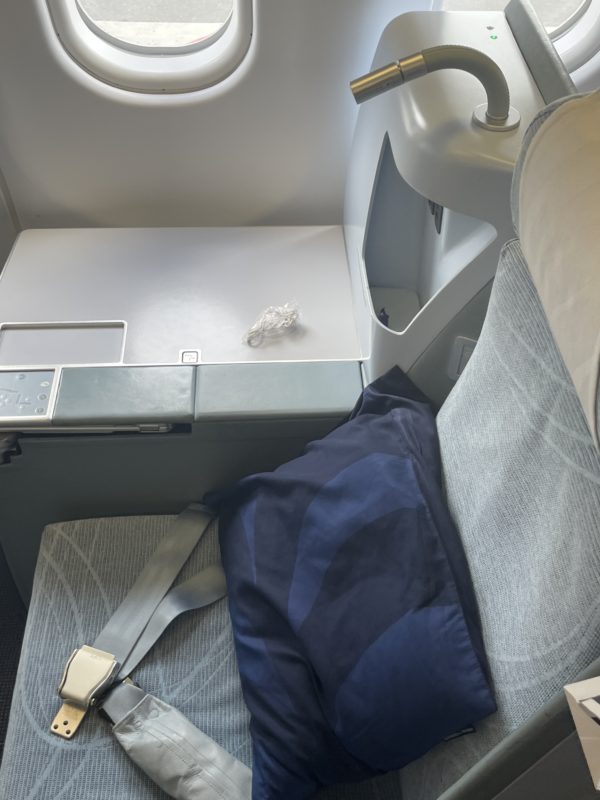seat in an airplane with a seat belt and pillow