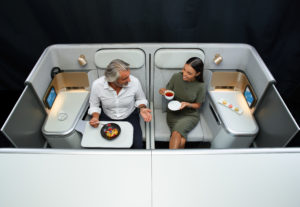 a man and woman sitting in a chair with plates and food