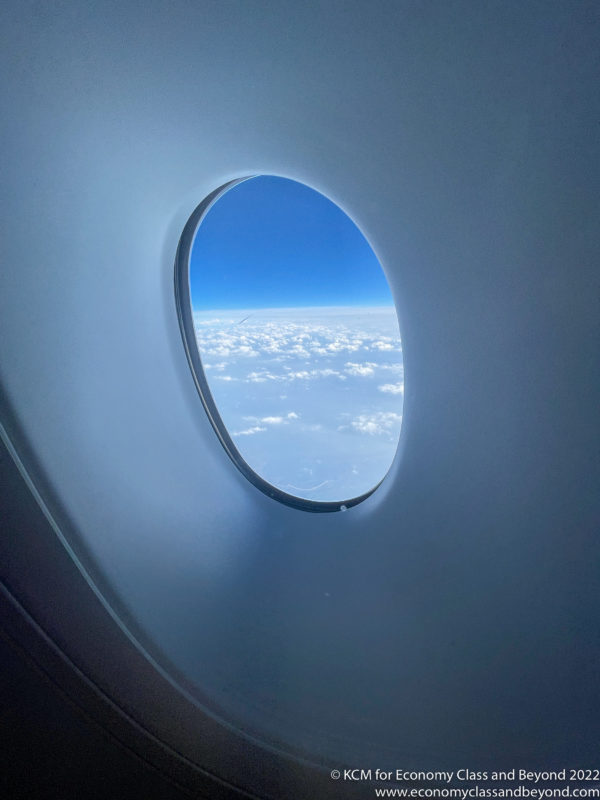 a window with a view of clouds and blue sky