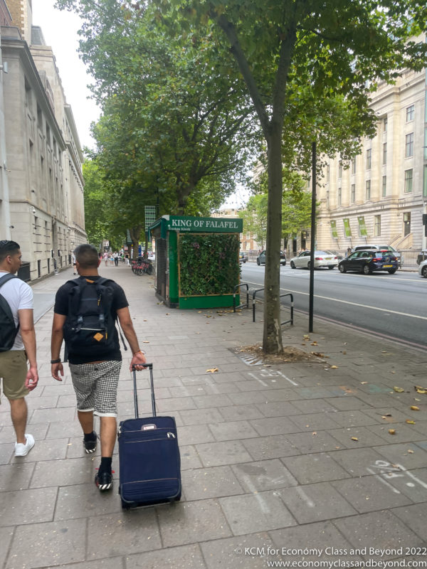 a man walking on a sidewalk with a suitcase