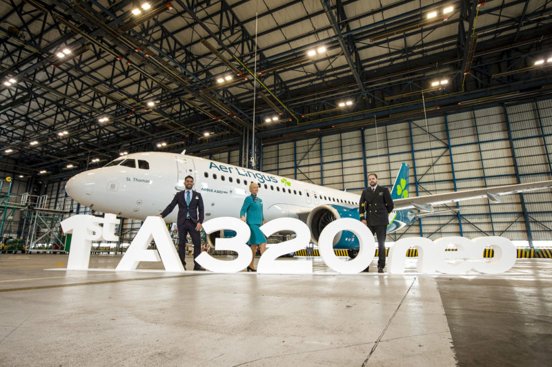 a group of people standing in front of a large white sign in a hangar