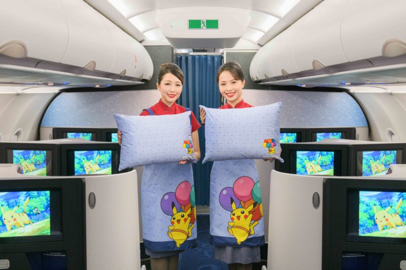 two women holding pillows in an airplane