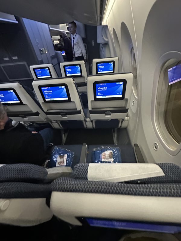 a group of people sitting in a plane with monitors