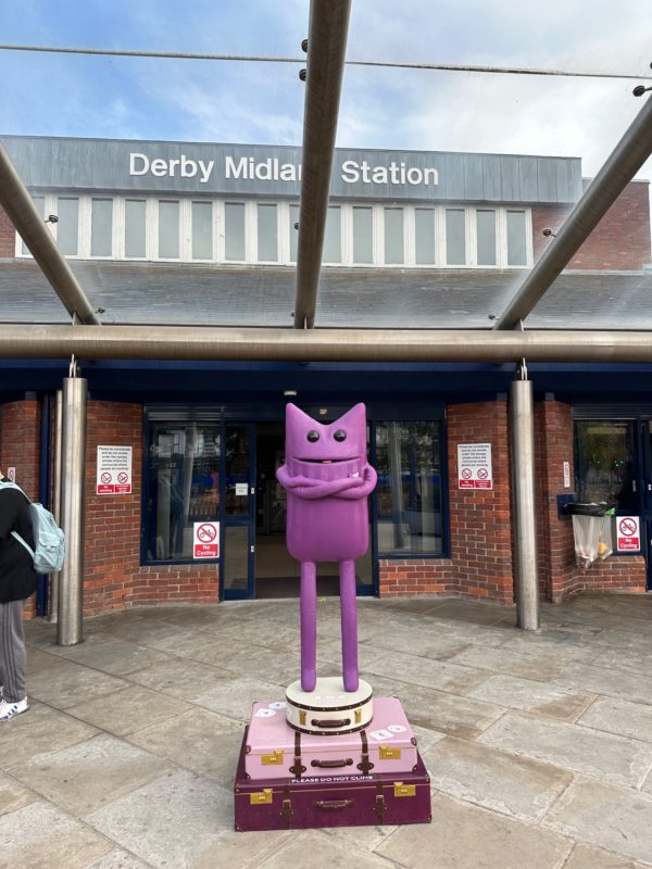 a purple cat statue in front of a building