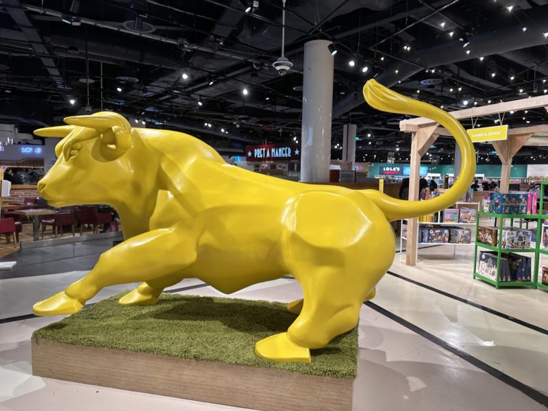 a yellow bull statue in a mall