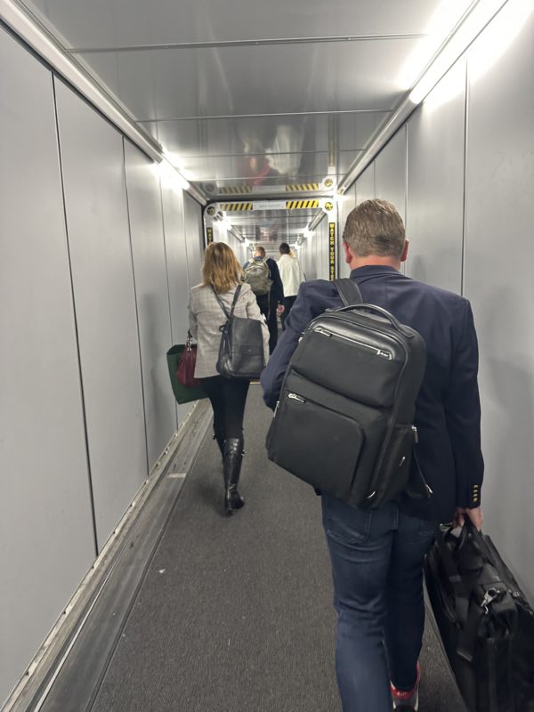 a man and woman carrying luggage in a hallway