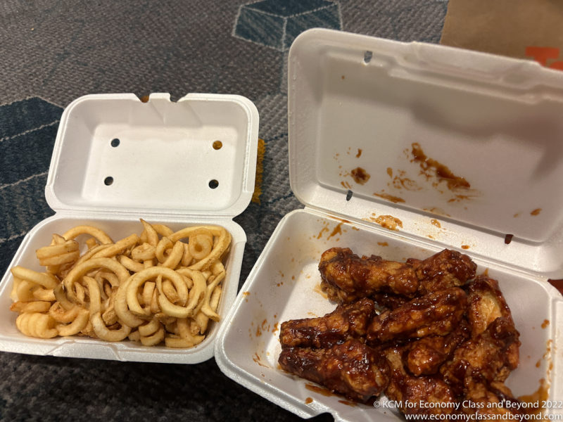 a container of food with wings and noodles