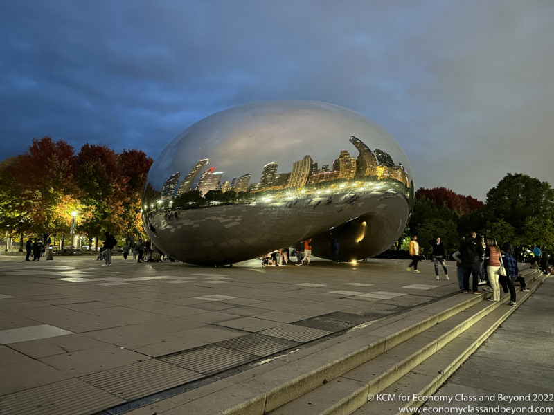 a large reflective object with a city in the background