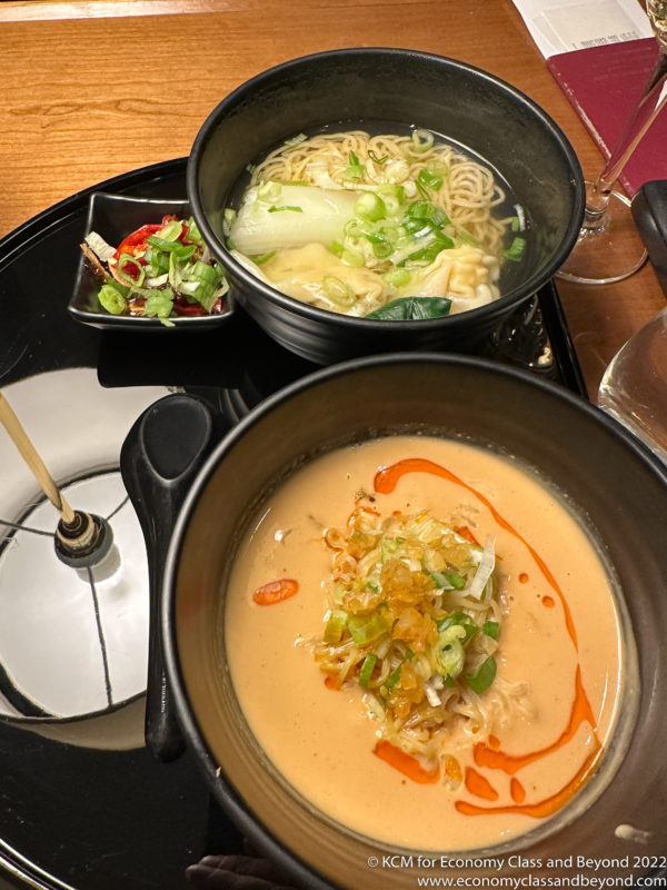 bowls of soup and noodles on a black plate
