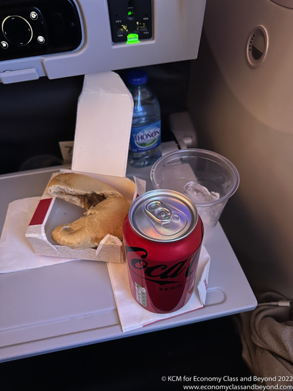a can of soda and a sandwich on a tray