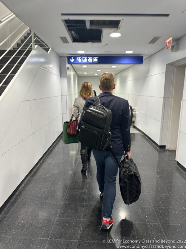 a man and woman carrying luggage in a hallway