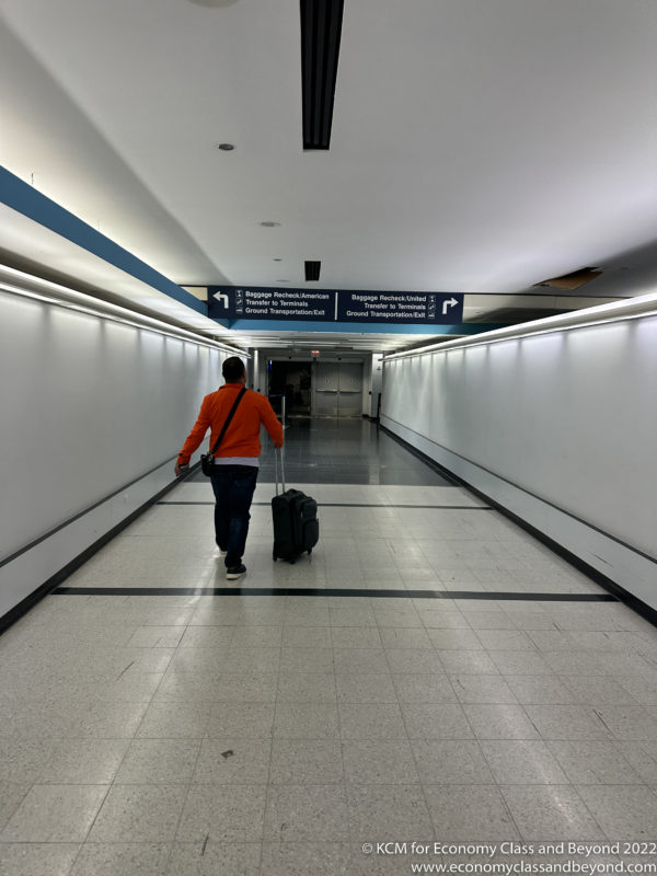 a man walking with luggage in a hallway