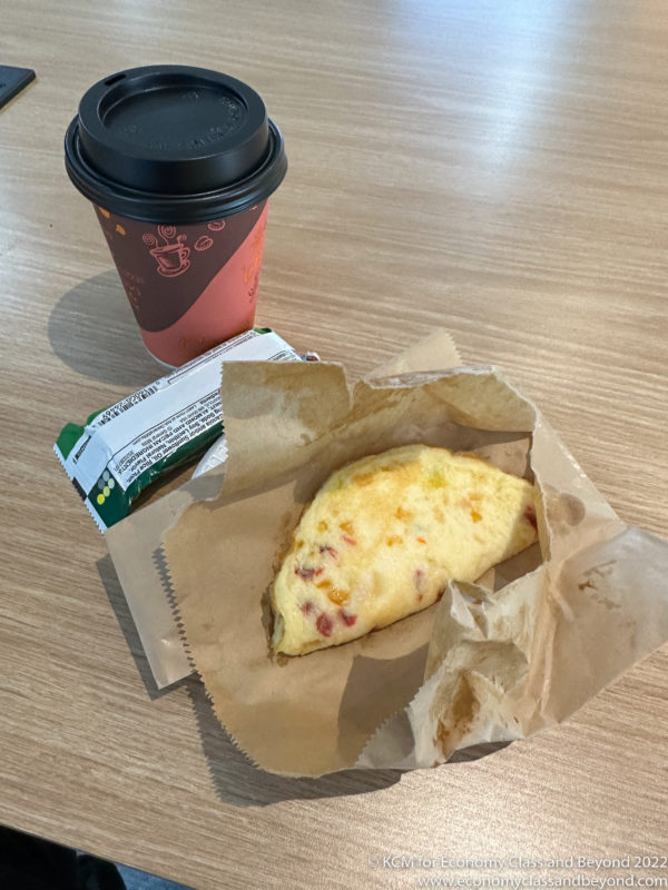 a food in a bag next to a coffee cup