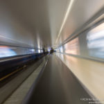 a blurry image of a person standing on a moving walkway