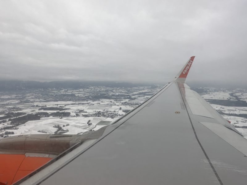 an airplane wing with snow and land in the background